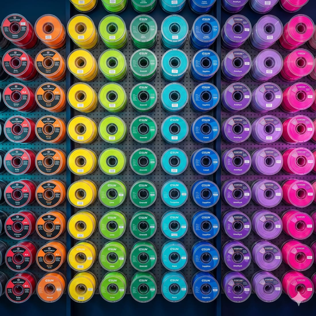 A wall of colour-sorted filament spools